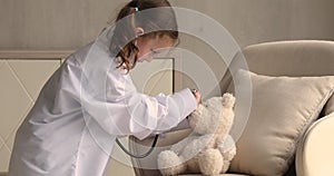 Little girl play doctor with plush toy bear at home