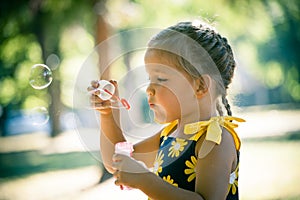 Little girl play in park blow soap bubbles profile close up