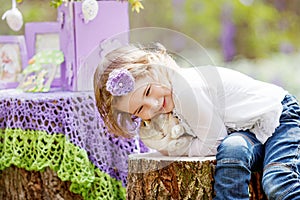 Little girl  play with real rabbit in the garden. Laughing child at Easter egg hunt with  pet bunny. Spring outdoor fun for kids