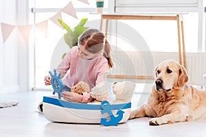 Little girl play with sea ship with golden retriever dog