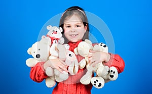 Little girl play with soft toy teddy bear. Lot of toys in her hands. Childhood concept. Collecting toys hobby