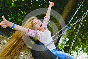 Little girl at playground. Child playing outdoors in summer. Teenager on a swing.