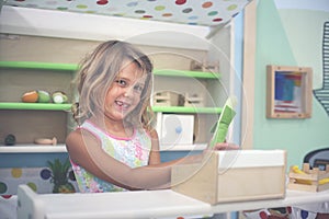 Little girl in playground. Girl playing with children cash register. Looking at camera.