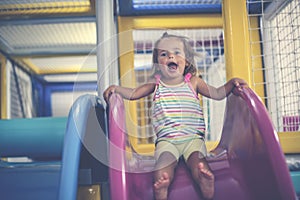 Little girl in playground. Happy little girl sitting on toboggan