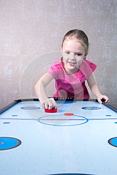 Little girl is playing in air hockey