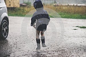 Little girl playing alone outside in bad weather