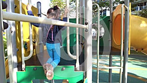 Little girl playing alone at the playground. View from behind. The footage may contain noise due to low light