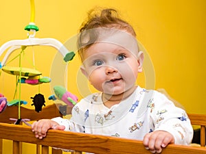 Little girl playing in the baby crib