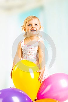 Little girl playing with balloons on a white background.