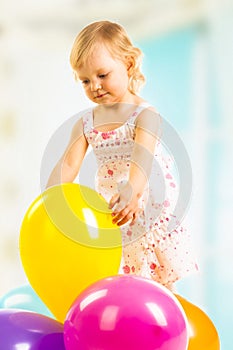 Little girl playing with balloons on a white background.