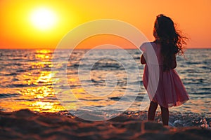 Little girl playing on the beach and enoying sunrise