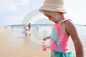 Little girl playing on the beach with her friends. Concept of summer vacation