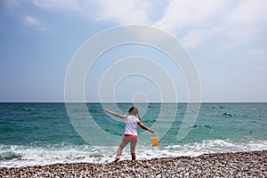 Little girl playing on the beach near blue sea