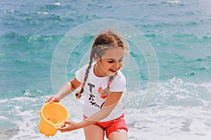 Little girl playing on the beach near blue sea