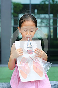 Little girl playing blowing with Simulate breathing of the lungs. Healthcare concept photo
