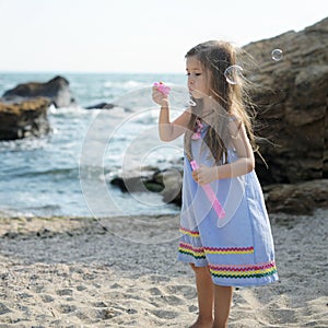 Little girl playing blowing soap bubbles, happy childhood concept