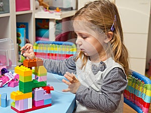 Little girl is playing with building bricks