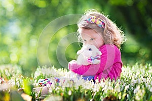 Little girl playing with bunny on Easter egg hunt