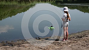 Little girl playing with carp fishing bait boat. Kid fishing with dad. Child near dirty water in the river. Water