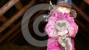 Little girl playing with a cat in winter.