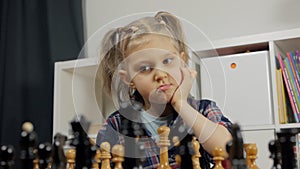 A little girl playing chess. The child plays chess at home, The development of logical thinking in children.