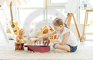 Little girl playing chess with teddy