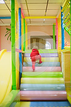 little girl playing in the children's playroom with colorful balls, toys in the entertainment center