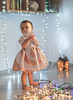 Little girl playing with christmas lights in the house