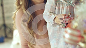 Little girl playing with Christmas toy near the Christmas tree with mother