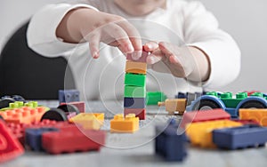 Little girl playing with colorful construction plastic cubes