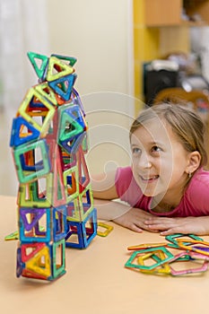 Little girl playing colorful magnet plastic blocks kit at indoor playground. girl made a toy robot. The child playing educational