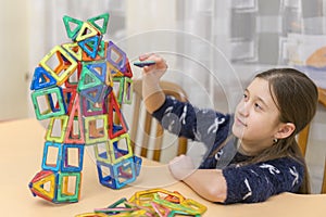 Little girl playing colorful magnet plastic blocks kit at indoor playground. girl made a toy robot. The child playing educational