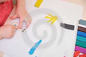 Little girl playing with colorful modeling clay on the table. Home Education game with clay.