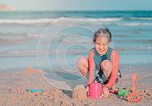 Little girl playing with colorful plastic toy and sand on the beach for kid summer vacation concept