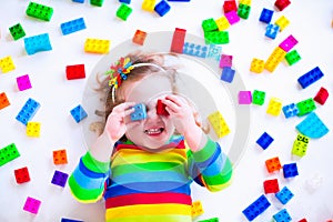 Little girl playing with colorful toy blocks