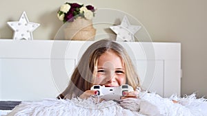 A little girl is playing a computer console on a sofa in a bright room. Concurrent games for children. Joystick for