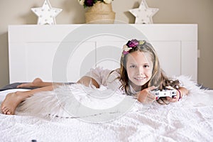 A little girl is playing a computer console on a sofa in a bright room. Concurrent games for children. Joystick for