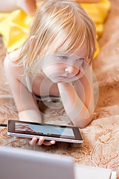 Little girl playing computer game using tablet indoors.