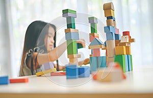 Little girl playing with construction toy blocks building a tower