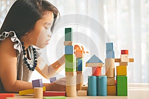 Little girl playing with construction toy blocks building a tower