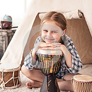 Little girl playing on djembe drums