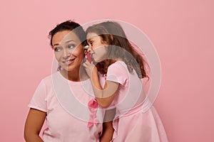 Little girl playing doctor with her mother. Beautiful African American woman with baby girl in pink with pink ribbon, symbol of