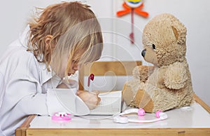 Little girl playing a doctor with her teddy bear