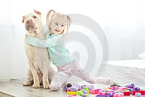 Little girl is playing with a dog in the room. The concept of li