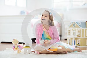 Little girl playing with doll house. Kid with toys