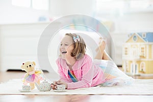 Little girl playing with doll house. Kid with toys