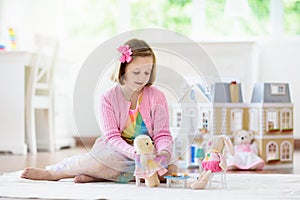 Little girl playing with doll house. Kid with toys