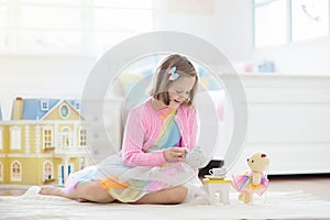 Little girl playing with doll house. Kid with toys