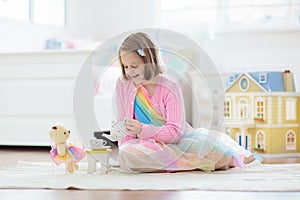 Little girl playing with doll house. Kid with toys