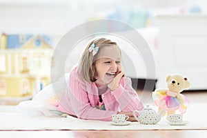 Little girl playing with doll house. Kid with toys